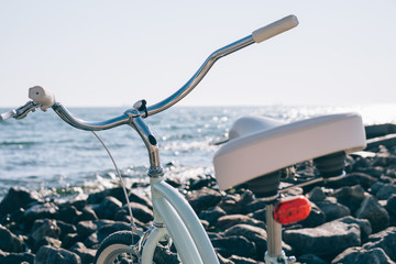 Female retro bicycle on the beach on a background of blue sea on a sunny day
