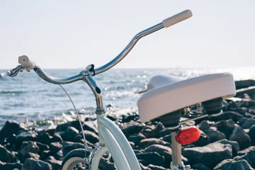 Gordijnen Female retro bicycle on the beach on a background of blue sea on a sunny day © progressman
