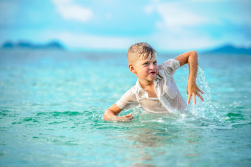 As if a bird: a close-up portrait of a handsome boy in wet slim fit shirt jumps and flutters over the water, a lot of splashes and fun. Toothless smile and dancing