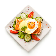 Grilled salmon with fried egg and vegetables on white background 
