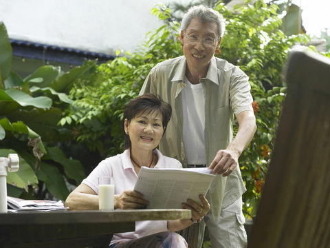 Couple Reading Newspaper In The Garden