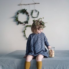 Kleines Mädchen mit Kranz auf dem Kopf nascht Kekse zu Weihnachten