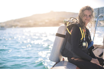 Beautiful girl wearing scuba diver's equipment, sitting on a boat © merla