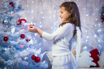 Christmas angel. Child Christmas angel costume with candle. beautiful girl in white blue interior Christmas near the Christmas tree.