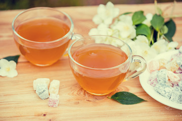 Two cups of green tea with jasmine decorated with a turkish delight on wooden table