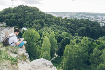 man sits on the peak and texting