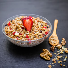 Tasty muesli with strawberries and blueberries on dark table. Diet natural breakfast. Flat lay, top view