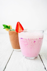 Strawberry smoothie and chocolate banana smoothie on white wood background. Tasty fresh milkshake