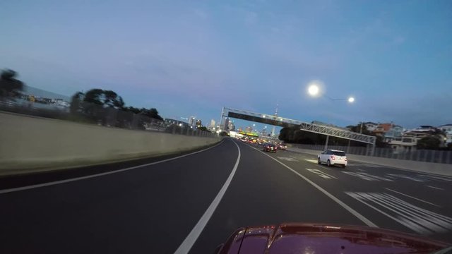 Car driving into Auckland city at dusk.  There are 43,000 more cars on Auckland's roads than this time last.