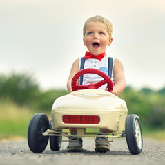 freudig motiviert - kleiner Junge im Tretauto