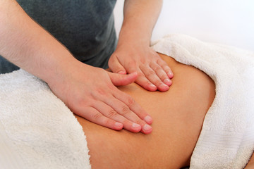 Fototapeta na wymiar Belly massage in massage studio. Close up of hands massaging female abdomen. Masseur massaging girls belly. Therapist applying pressure on belly. In spa center. Body and health care, medicine concept.