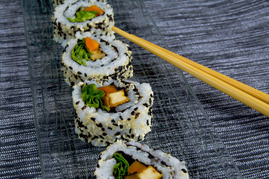 Vegan sushi on glass plate with chopsticks