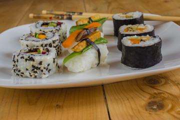 Vegan sushi on plate on wood table with chopsticks