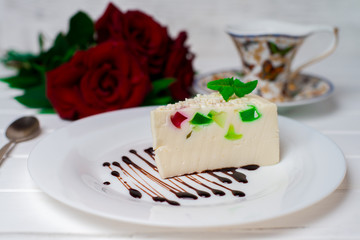 Fruit jelly with pieces of apricot on a plate and a spoon on an old wooden table. Selective focus
