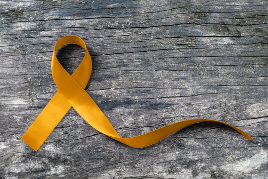 Gold ribbon awareness symbolic color for Childhood cancer on old aged wood