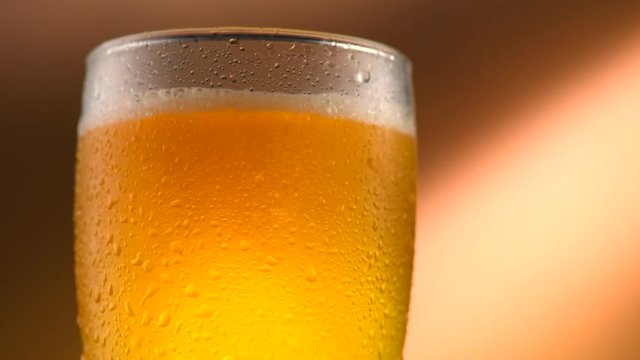 Cold beer pouring into a glass with water drops. Craft beer close up. Rotation 360 degrees. 4K video 3840x2160