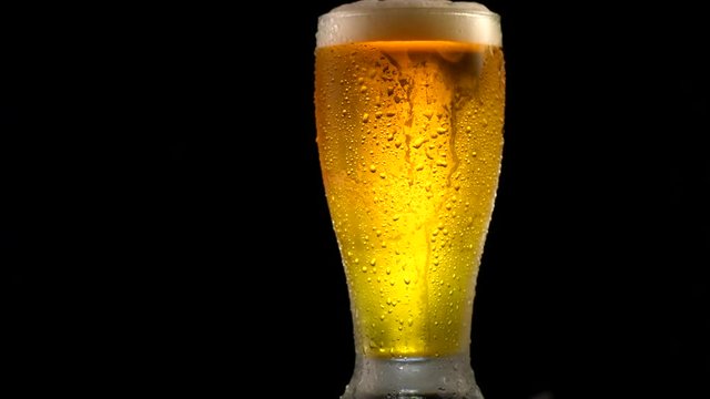 Cold beer in a glass with water drops. Craft beer close up. Rotation 360 degrees. 4K UHD video 3840x2160