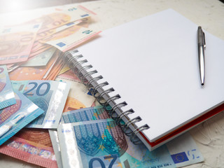 money Euro and a notebook with a pen, to dream, to record expenses, home finances, space for text