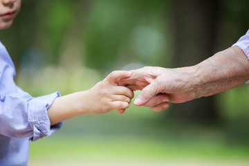Young boy holding great grandmother's hand