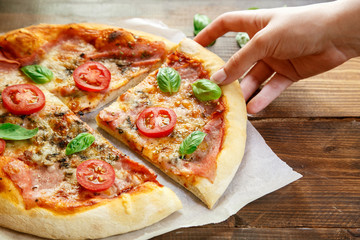 Pizza. Woman taking and eating fresh Italian margherita with salami, basil and tomato.