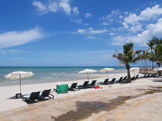 white sand beach with white umbrella and beach bed on a sunny day
