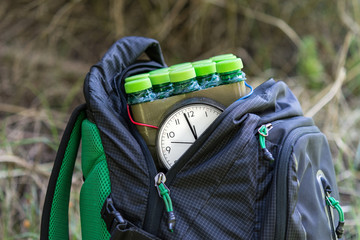 Dangerous timed bomb in backpack on grassy background.