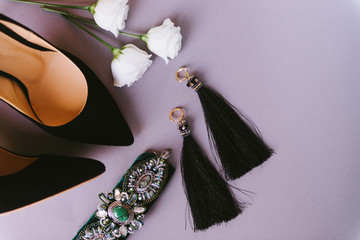 Women's fashion accessories placed on lilac background. Black leather high heels shoes, gorgeous...