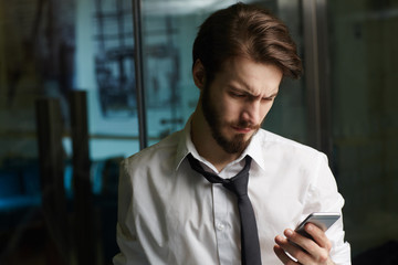 Tired businessman reading sms late in the evening