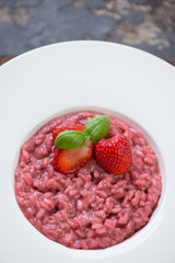 Close-up of strawberry risotto served in a white plate, vertical shot, elevated view