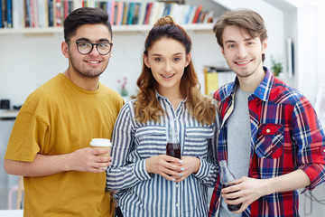 Happy students with drinks looking at camera