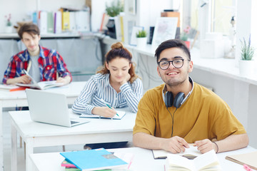 Happy guy with headphones sitting by desk at lesson