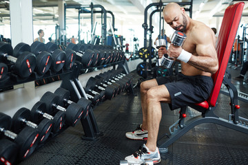 Fototapeta na wymiar Active man with barbells training in gym