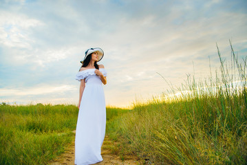 Woman in a white dress on an asshole in a green field
