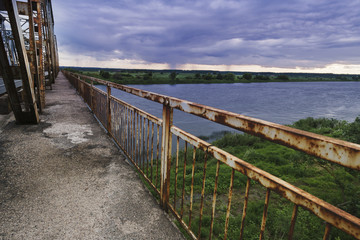 Fototapeta na wymiar View of the old bridge at the dark rainy day over a river.