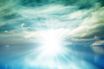 Fototapeta premium Bright sunset in blue sky with clouds over blue sea