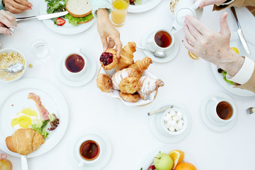 Human hand taking sweet bun during family breakfast