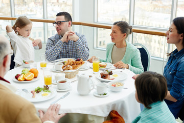 Obraz na płótnie Canvas Big family having talk by breakfast in restaurant