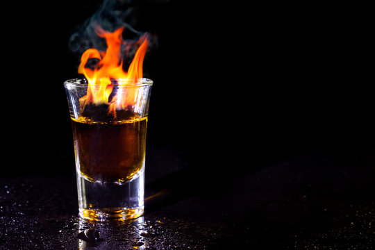 Hot alcoholic cocktail burning in shot glass.
