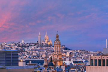 Fototapeta na wymiar Aerial view of Sacre-Coeur Basilica or Basilica of the Sacred Heart of Jesus at the butte Montmartre and Saint Trinity church at nice sunset, Paris, France