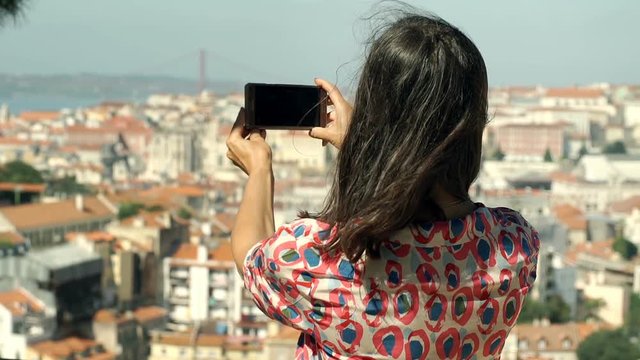 Woman doing photos of the city on smartphone, steadycam shot
