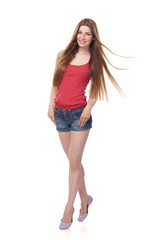 Naklejka premium Full length of smiling leggy young female in denim shorts and red top with beautiful long hair, isolated on white background