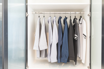 clothes hanging on rail in wooden white wardrobe