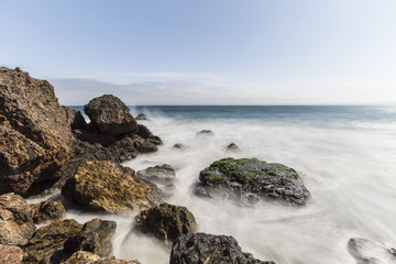 Fototapeta na wymiar Pacific coast rocks and waves with motion blur at Point Dume in Malibu, California.