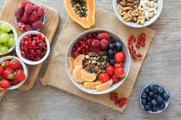 Paleo style breakfast, grain free muesli made with nuts and dried fruits, served with fresh berries, top view, selective focus