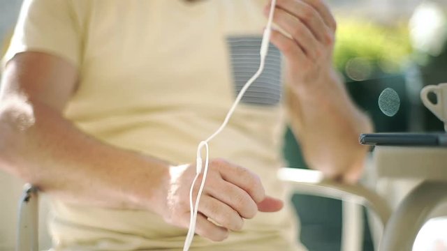 Man sitting in the cafe and trying to untangle earphones
