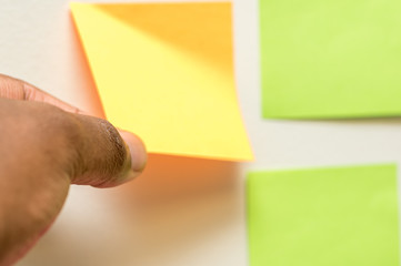 a colorful post it being pulled off white background