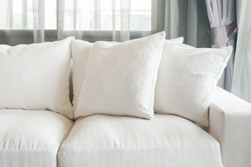 White color sofa and pillows with sheer curtain in background