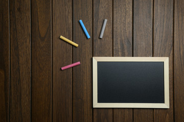 empty blackboard with chalks on vintage wooden background