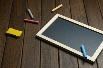 empty blackboard with chalks on vintage wooden background