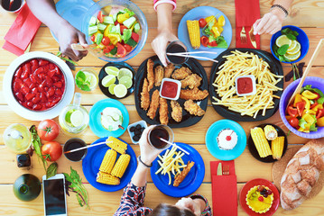 Top view of group of people having dinner together while sitting at wooden table. Food on the table. People eat fast food.
